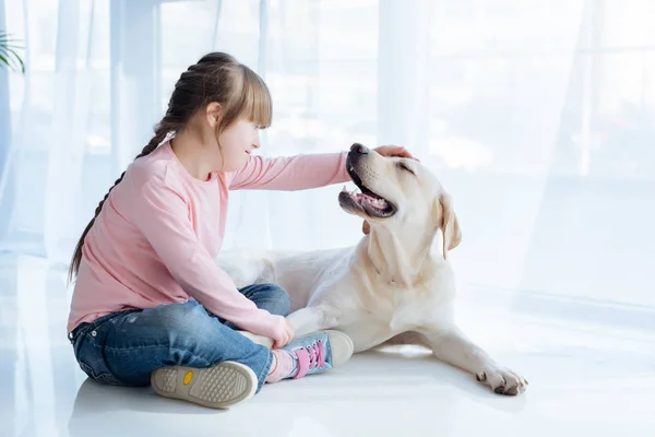 Little girl with down syndrome stroking Labrador retriever head — Stock Photo