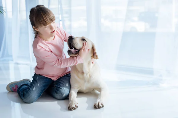 Kid with down syndrome playing with Labrador retriever — Stock Photo