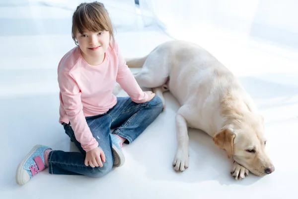 Top view of child with down syndrome and dog retriever in room — Stock Photo