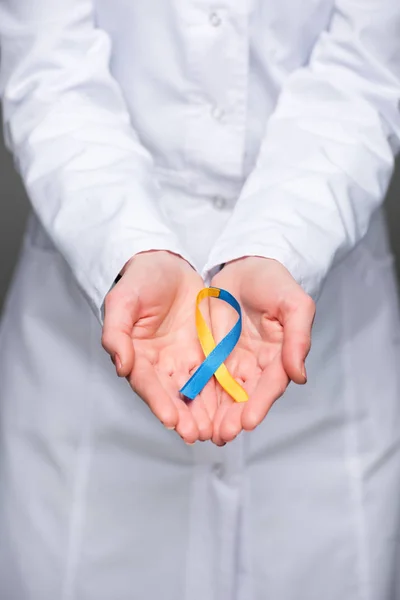 Female doctor hands holding Down Syndrome Day symbol blue and yellow ribbon — Stock Photo