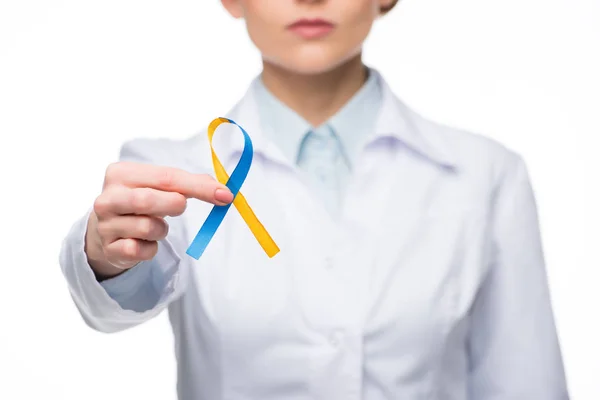 Médica feminina segurando fita azul e amarela para o Dia da Síndrome de Down isolada no branco — Fotografia de Stock