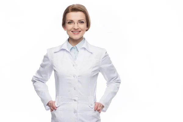 Молода усміхнена жінка-лікар стоїть ізольовано на білому — стокове фото