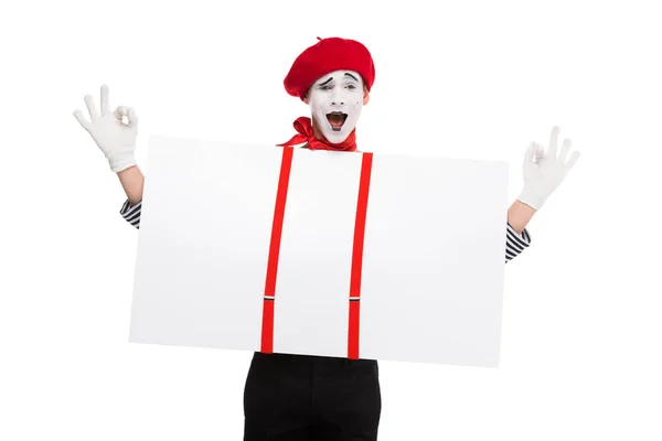 Happy mime holding empty board under susenders and showing ok sign isolated on white — Stock Photo