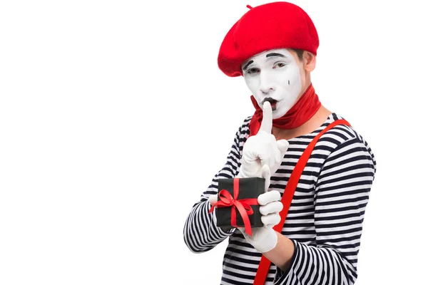 Mime holding present box and showing silence gesture isolated on white — Stock Photo