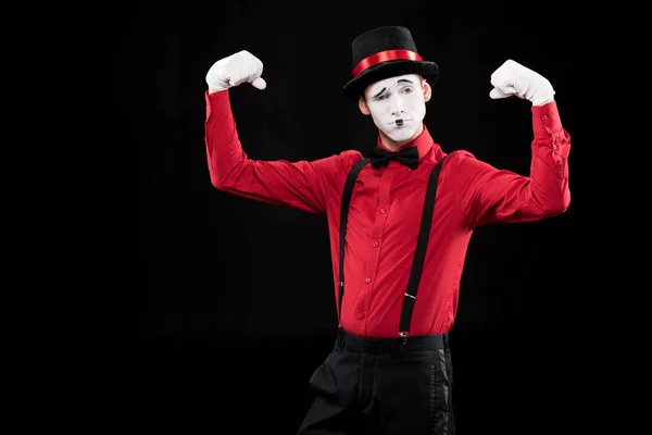 Mime showing muscles isolated on black — Stock Photo