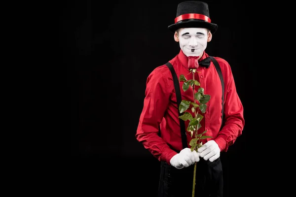 Mime sniffing red rose with closed eyes isolated on black — Stock Photo