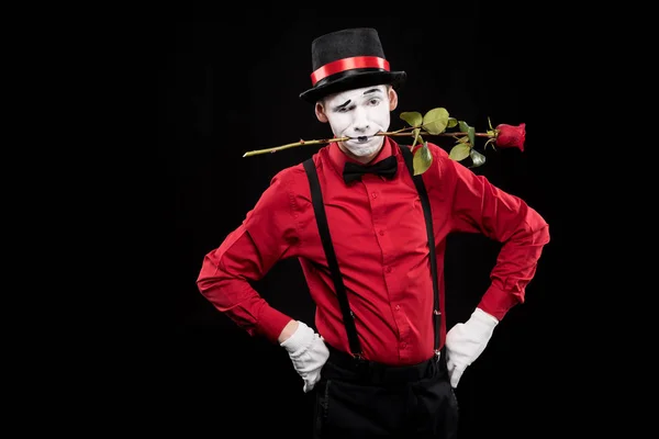 Mime grimacant et tenant rose rouge dans la bouche isolé sur noir — Photo de stock