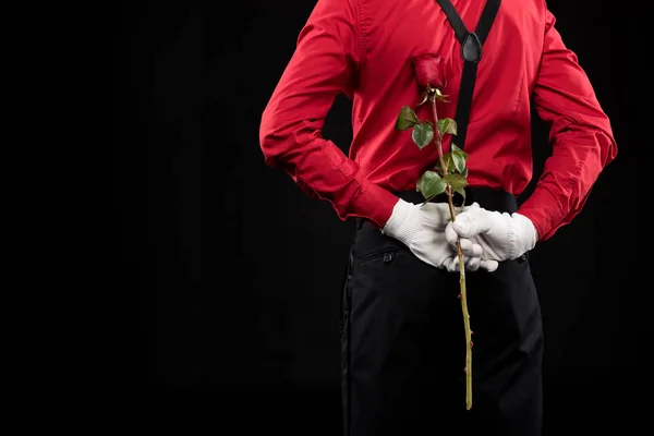 Cropped image of mime hiding rose behind back isolated on black — Stock Photo