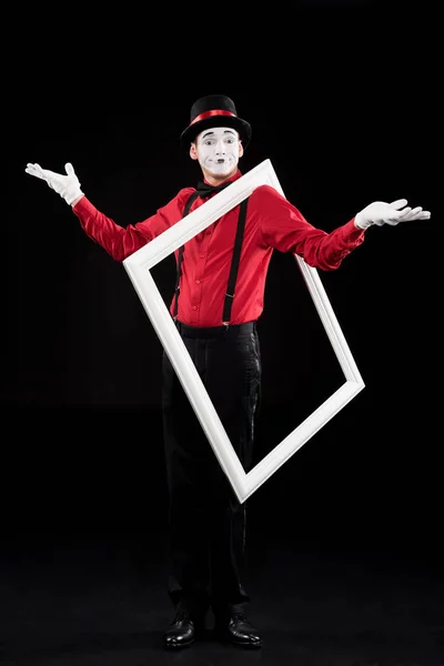 Mime showing shrug gesture and holding frame on shoulder isolated on black — Stock Photo