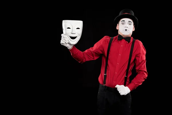 Scared mime holding white mask isolated on black — Stock Photo