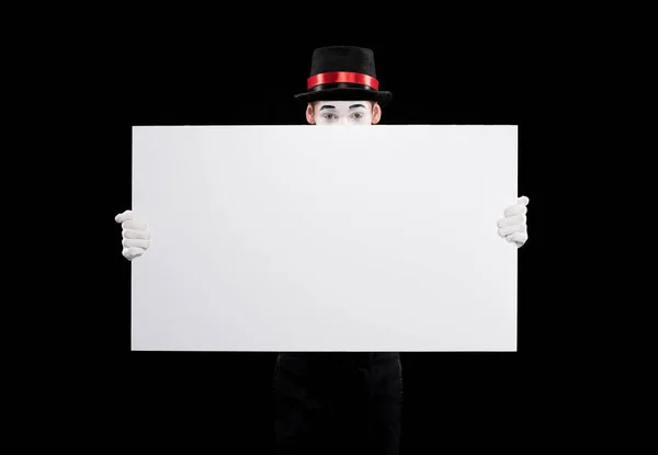 Mime looking out from empty board isolated on black — Stock Photo