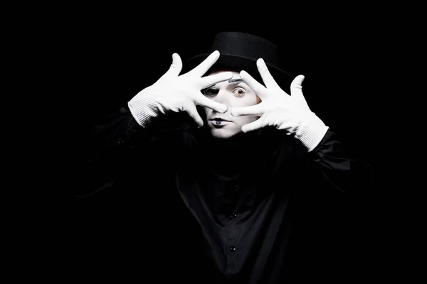 Mime looking at camera through spread fingers isolated on black — Stock Photo