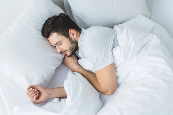 Vista dall'alto dell'uomo barbuto che dorme sul letto in camera da letto — Foto stock