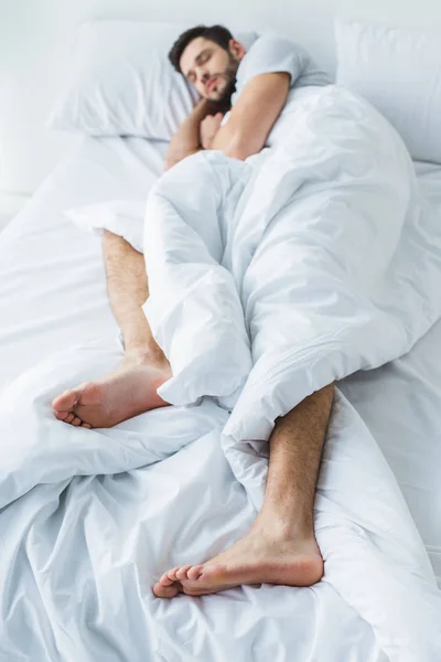 Selektiver Fokus des schlafenden Mannes auf weißem Bett — Stockfoto