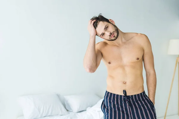 Schöner hemdloser Mann posiert morgens im Schlafzimmer — Stockfoto