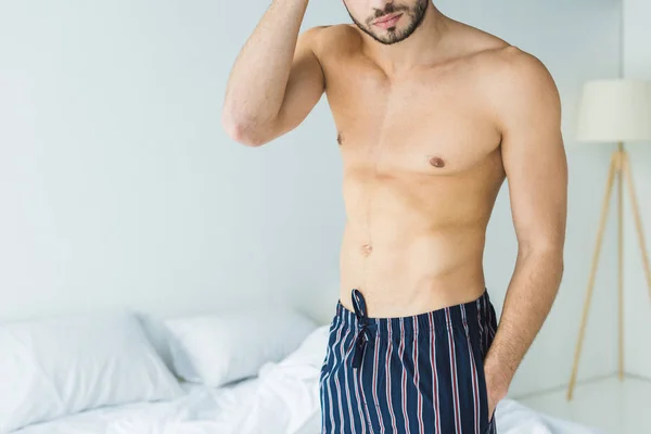 Обрізаний вид без сорочки чоловік стоїть в спальні вранці — стокове фото