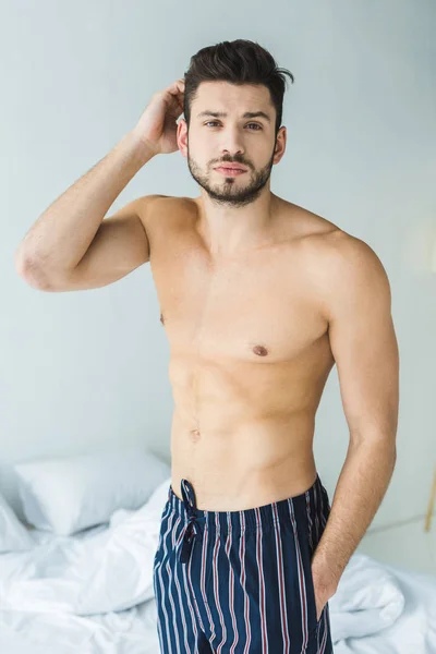 Schöner hemdloser Mann, der morgens im Schlafzimmer steht — Stockfoto