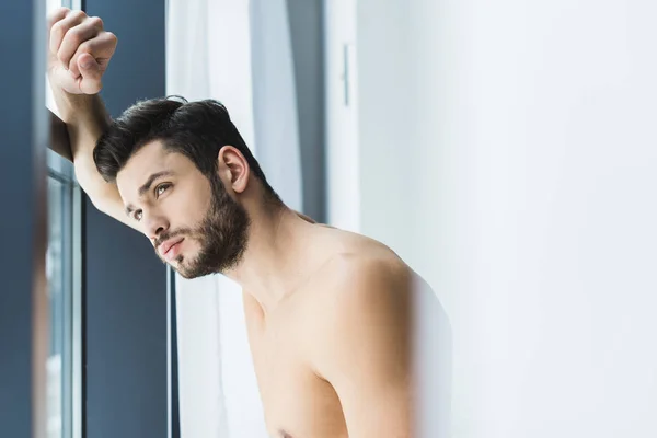 Pensive handsome shirtless man looking at window — Stock Photo