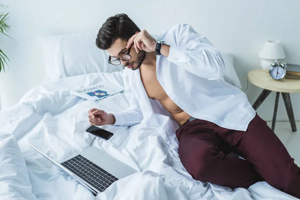 Handsome businessman using laptop on bed in the morning — Stock Photo