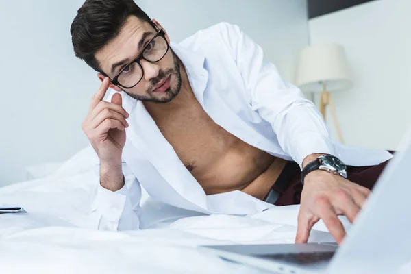 Bärtiger Geschäftsmann mit Brille am Morgen mit Laptop im Bett — Stockfoto