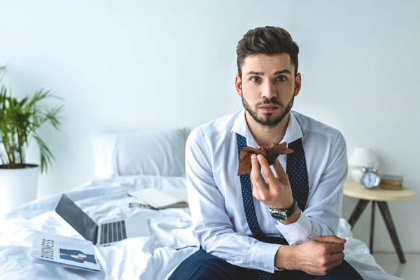 Uomo d'affari mangiare muffin sul letto con computer portatile e giornale — Foto stock