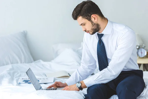 Handsome bearded businessman working with laptop in bedroom — Stock Photo