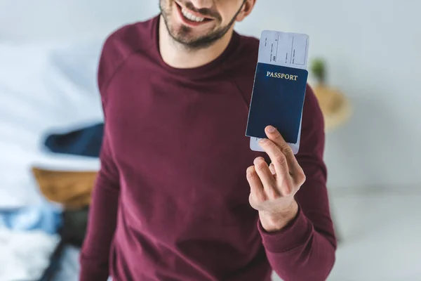 Vista ritagliata di uomo sorridente in possesso di passaporto e biglietto aereo — Foto stock