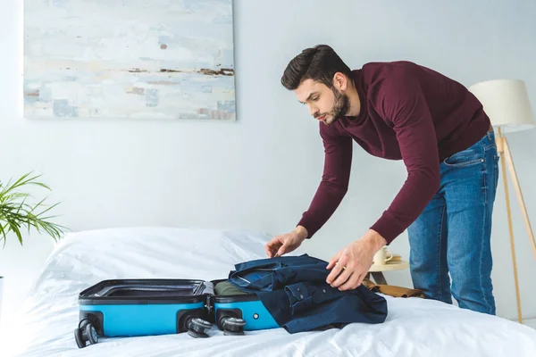 Homem bonito embalando roupas em saco de viagem para viagem — Fotografia de Stock