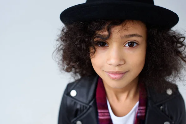 Close-up portrait of beautiful little child in leather jacket and hat looking at camera isolated on grey — Stock Photo