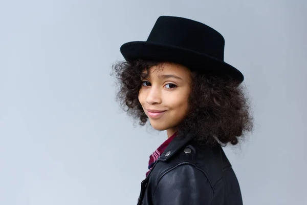 Close-up portrait of little child with curly hair in hat isolated on grey — Stock Photo