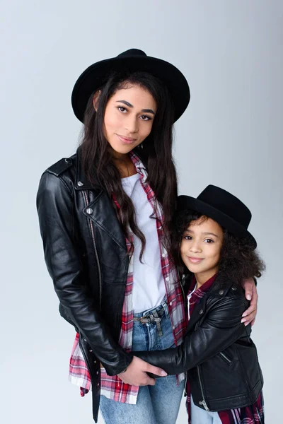 Mother and daughter in similar clothes embracing and looking at camera isolated on grey — Stock Photo