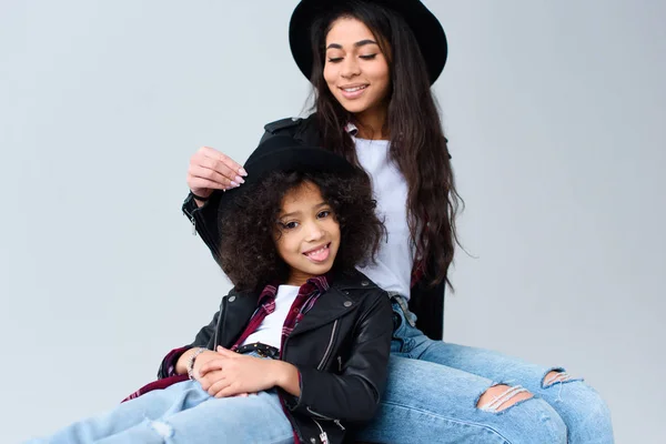 Happy mother and daughter in similar clothes spending time together isolated on grey — Stock Photo