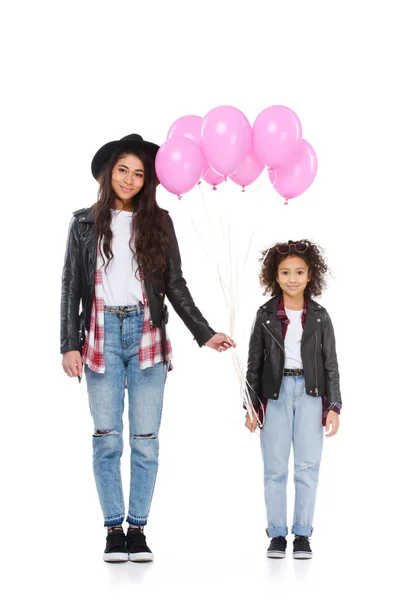 Stylish young mother and daughter in similar clothes with pink balloons isolated on white — Stock Photo