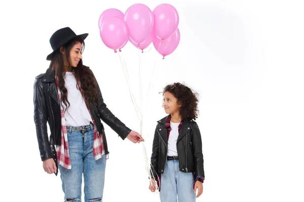Glückliche Mutter und Tochter in ähnlicher Kleidung mit rosa Luftballons auf weißem Grund — Stockfoto