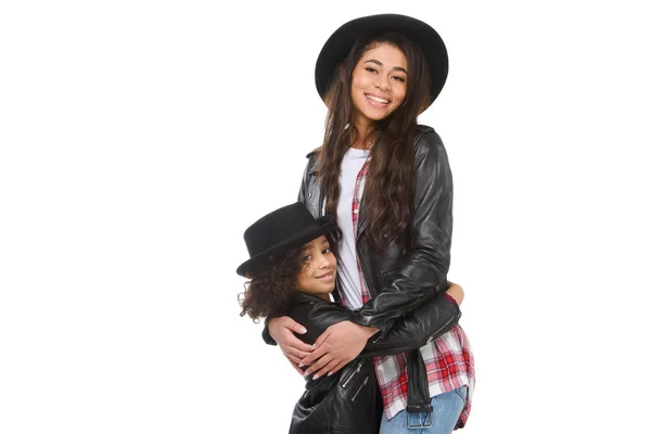 Stylish young mother and daughter in leather jackets embracing and looking at camera isolated on white — Stock Photo