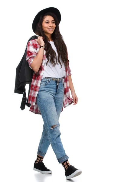 Beautiful walking young woman in stylish plaid shirt and leather jacket isolated on white — Stock Photo