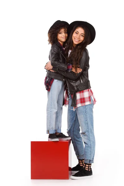 Happy embracing mother and daughter in leather jackets and hats mother and daughter isolated on white — Stock Photo