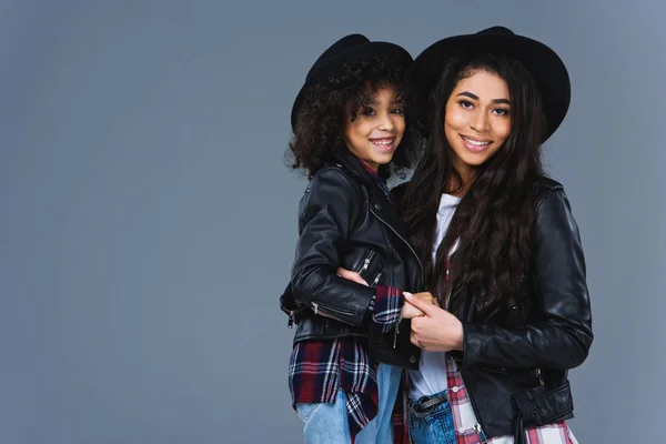 Young embracing mother and daughter in leather jackets isolated on grey — Stock Photo