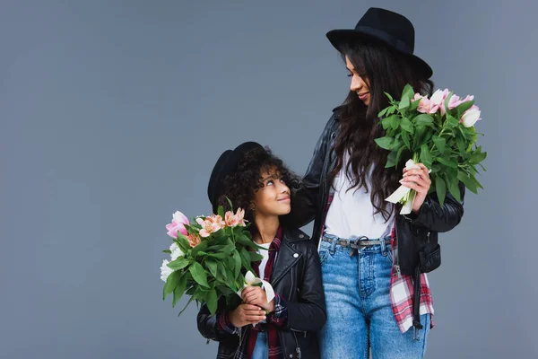 Beautiful mother and daughter with beautiful bouquets isolated on grey — Stock Photo