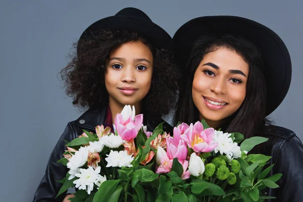 Close-up portrait of mother and daughter with beautiful bouquets isolated on grey — Stock Photo