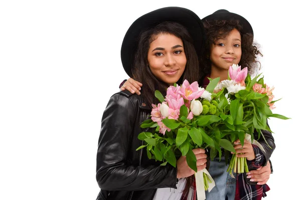 Embracing mother and daughter with beautiful bouquets isolated on white — Stock Photo
