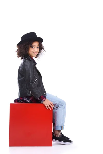 Niño pequeño y elegante sentado en cubo rojo aislado en blanco - foto de stock