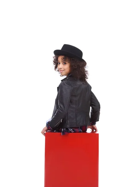 Vista trasera de un hermoso niño sentado en cubo rojo aislado en blanco - foto de stock