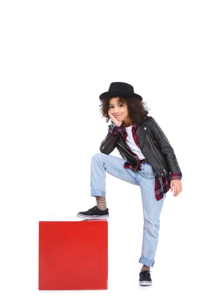Beautiful little child in stylish clothing standing on red cube isolated on white — Stock Photo