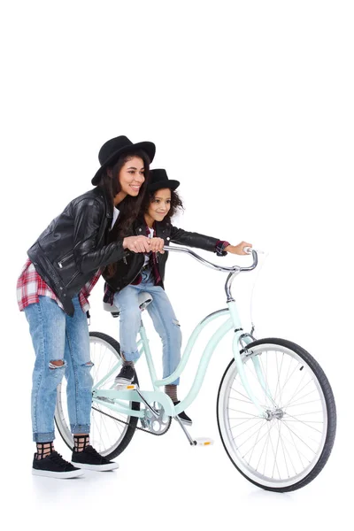 Madre enseñando a su hija a andar en bicicleta aislada en blanco - foto de stock