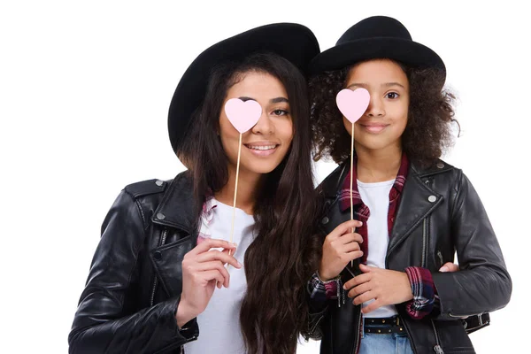 Mère et fille couvrant les yeux avec des symboles de coeur sur des bâtons isolés sur blanc — Photo de stock