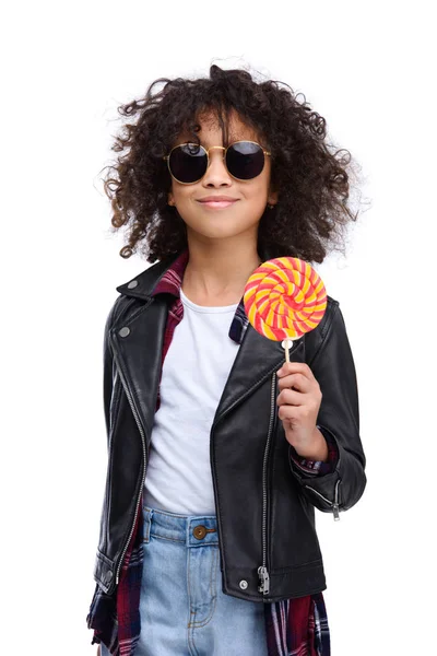 Linda criança em jaqueta de couro e óculos de sol com pirulito isolado no branco — Fotografia de Stock
