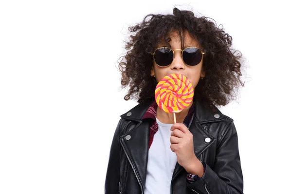 Beautiful little child in leather jacket and sunglasses eating lollipop isolated on white — Stock Photo
