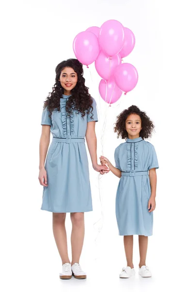 Мати і дочка в подібних сукнях з купою рожевих кульок ізольовані на білому — стокове фото