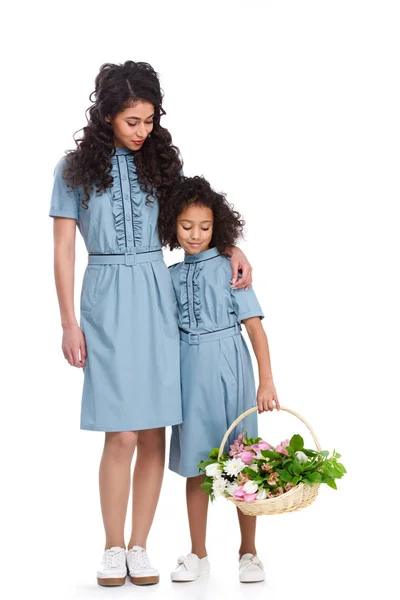 Young mother and daughter with basket of flowers isolated on white — Stock Photo